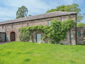 A stone building with a tiled roof, a green door, and a small arched window. - 2 bedroom accommodation in Carlisle (Carlisle)