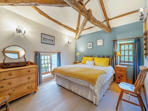 A bedroom with a large bed, wooden dresser, and a chair. - 2 bedroom accommodation in Carlisle (Carlisle)