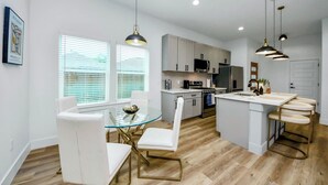 A modern kitchen with white cabinets, a central island, and pendant lighting.
