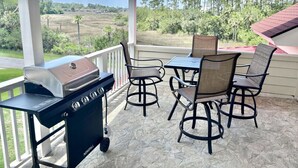 Eine überdachte Terrasse mit Grill, Tisch und Stühlen mit Blick auf eine ländliche Landschaft.