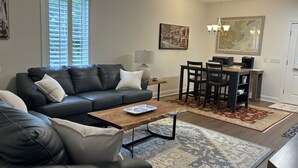 Ein modernes Wohnzimmer mit einem dunkelbraunen Ledersofa, einem Holztisch und einem Essbereich mit einem dunklen Holztisch und Stühlen.