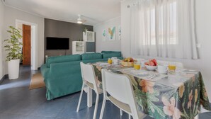 En moderne stue med sofa, spisebord og fjernsyn.