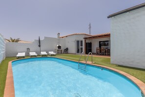 A swimming pool with a ladder, white lounge chairs, and a patio area with a table and chairs. - Holiday Home 'Betta' with Private Pool, Garden and Wi-Fi (Costa Calma)