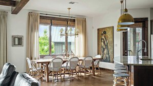 A dining area with a wooden table and chairs, a chandelier, and a painting on the wall. - Lake Travis Luxe Villa | 4BR | Pickleball | BBQ (Lake Travis)