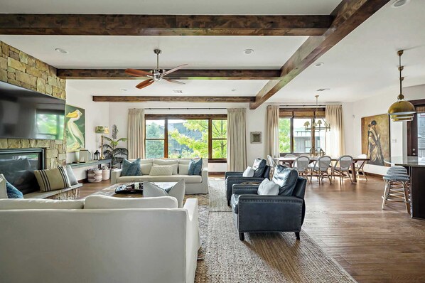 A spacious living room with a fireplace, a dining area, and a kitchen with a bar.