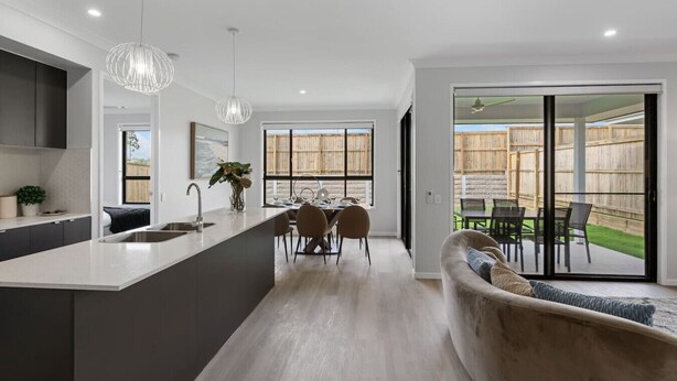 A modern kitchen with a central island, dining area with chairs, and a sliding glass door leading to a backyard. - 5BR Sleep 10 Family House | Patio Kitchen Garage (Park Ridge)