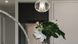 A modern kitchen with a white island, a stainless steel sink, and a decorative vase with flowers. - 5BR Sleep 10 Family House | Patio Kitchen Garage (Park Ridge)