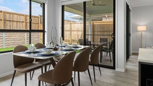 A modern dining area with a large table set for four, surrounded by chairs. - 5BR Sleep 10 Family House | Patio Kitchen Garage (Park Ridge)