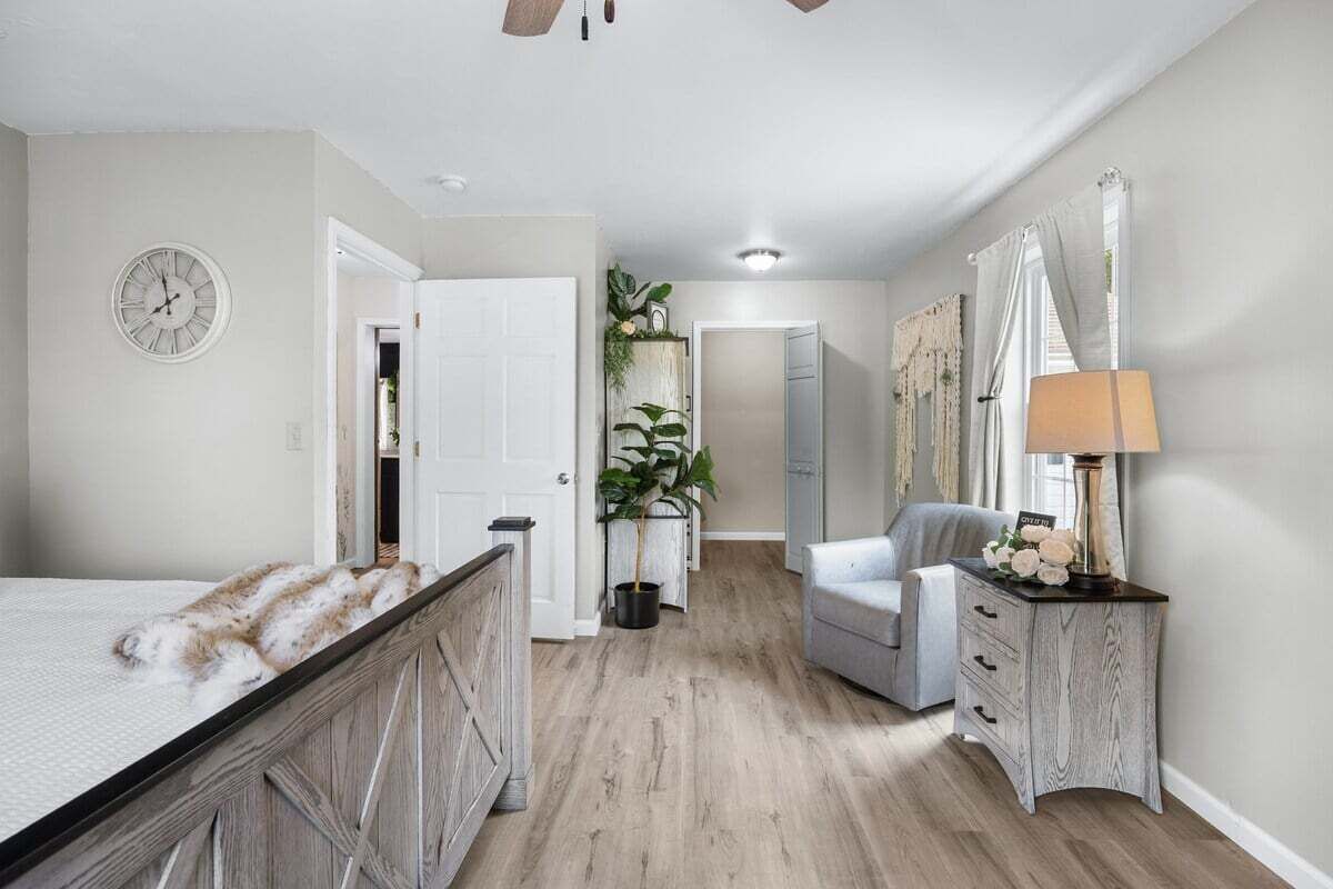 A bedroom with a bed, a dresser, a chair, a lamp, and a clock on the wall.