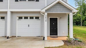 Un immeuble résidentiel à deux étages, doté d’un garage, d’un porche et d’une pelouse bien entretenue.