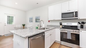 A modern kitchen with white cabinets, a stainless steel dishwasher, a built-in oven, and a microwave above the stove. - Hot Tub King Suite 8 min to Downtown Denver (Denver)