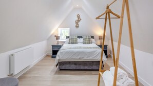 A bedroom with a bed, bedside tables, a hanging light, a radiator, and a wooden swing.