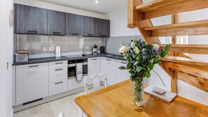A modern kitchen with grey cabinets, a wooden dining table, and a vase of flowers.