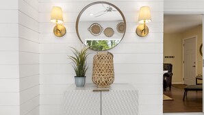 A modern interior with a white cabinet, a potted plant, a decorative mirror, and two wall-mounted lamps.