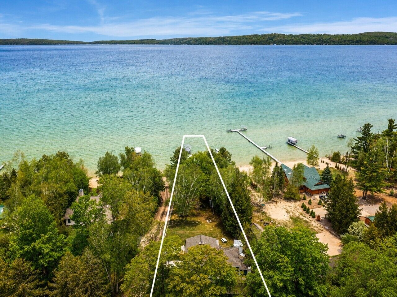 A lakeside property with a dock, cabins, and a large body of water.