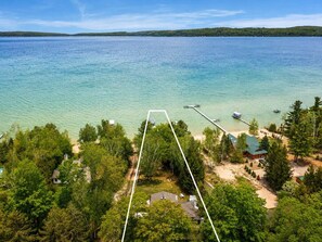 A lakeside property with a dock, cabins, and a large body of water.
