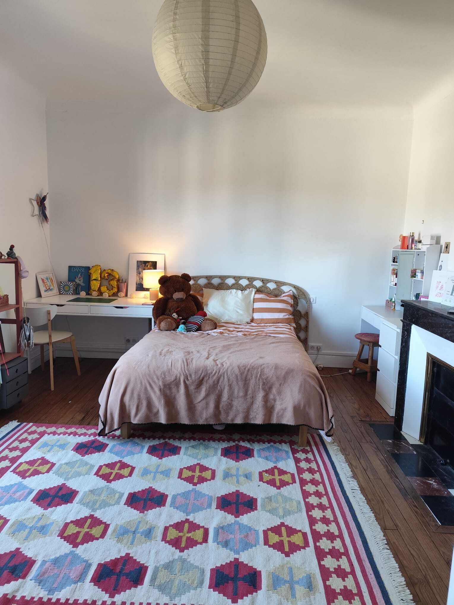 Un dormitorio con cama, escritorio y chimenea.