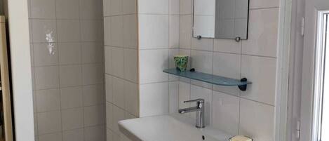 A bathroom with a white sink, a mirror, and a shower area.