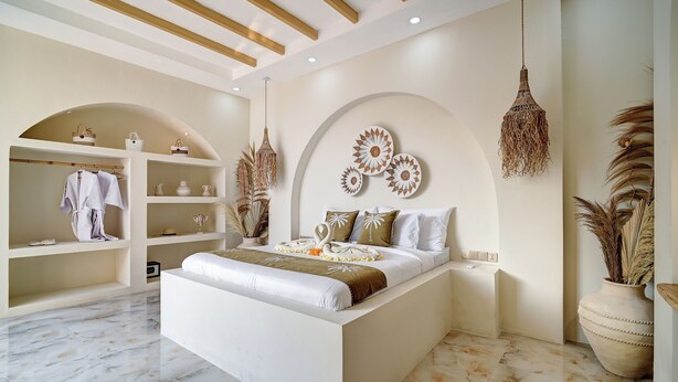 A modern bedroom with a large bed, built-in shelving, decorative wall art, and hanging lamps.
