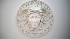 Un élément de décoration murale circulaire, de couleur blanche, au motif classique.