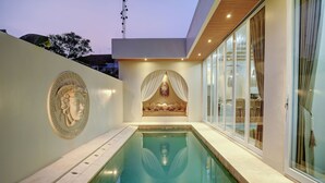 Une piscine intérieure moderne offrant une vue dégagée sur le bassin, un mur décoratif orné d’un emblème circulaire et un espace détente doté d’un auvent.