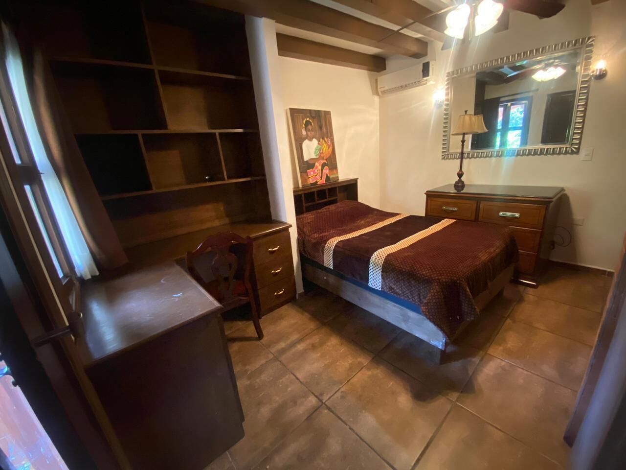 Une chambre à coucher comprenant un lit, un bureau, une chaise, une commode et une armoire.