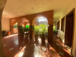 A covered corridor with brick arches, potted plants, and a tiled floor. - Loft for executives/students, furnished and equipped, Internet, cable TV (Monterrey)