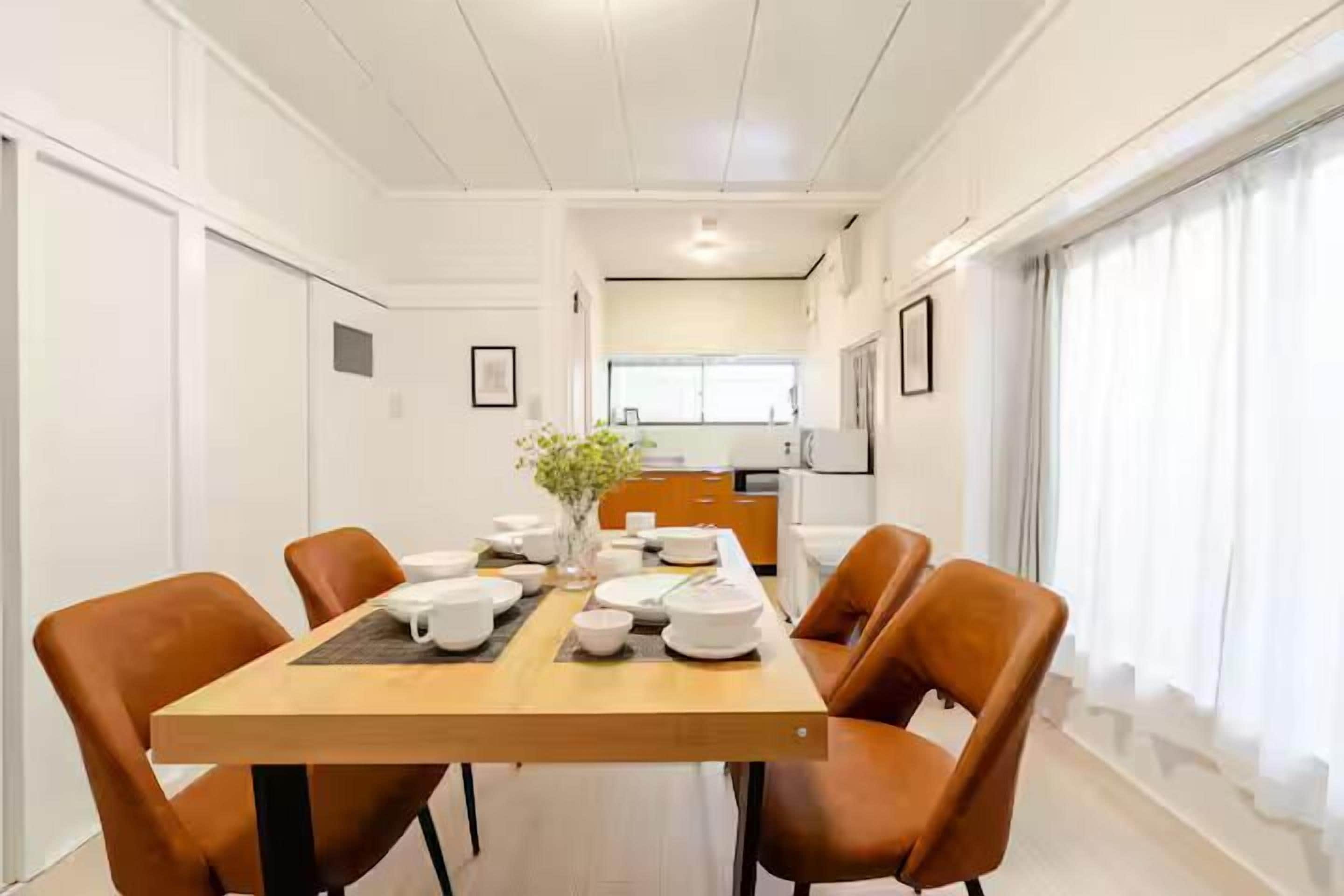 A dining area with a wooden table set for four, surrounded by four brown chairs.