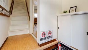 En trappa leder upp till ett rum med en vit vägg och ett skåp. På väggen finns det två skyltar: den ena förbjuder rökning och den andra förbjuder både rökning och användning av e-cigaretter.