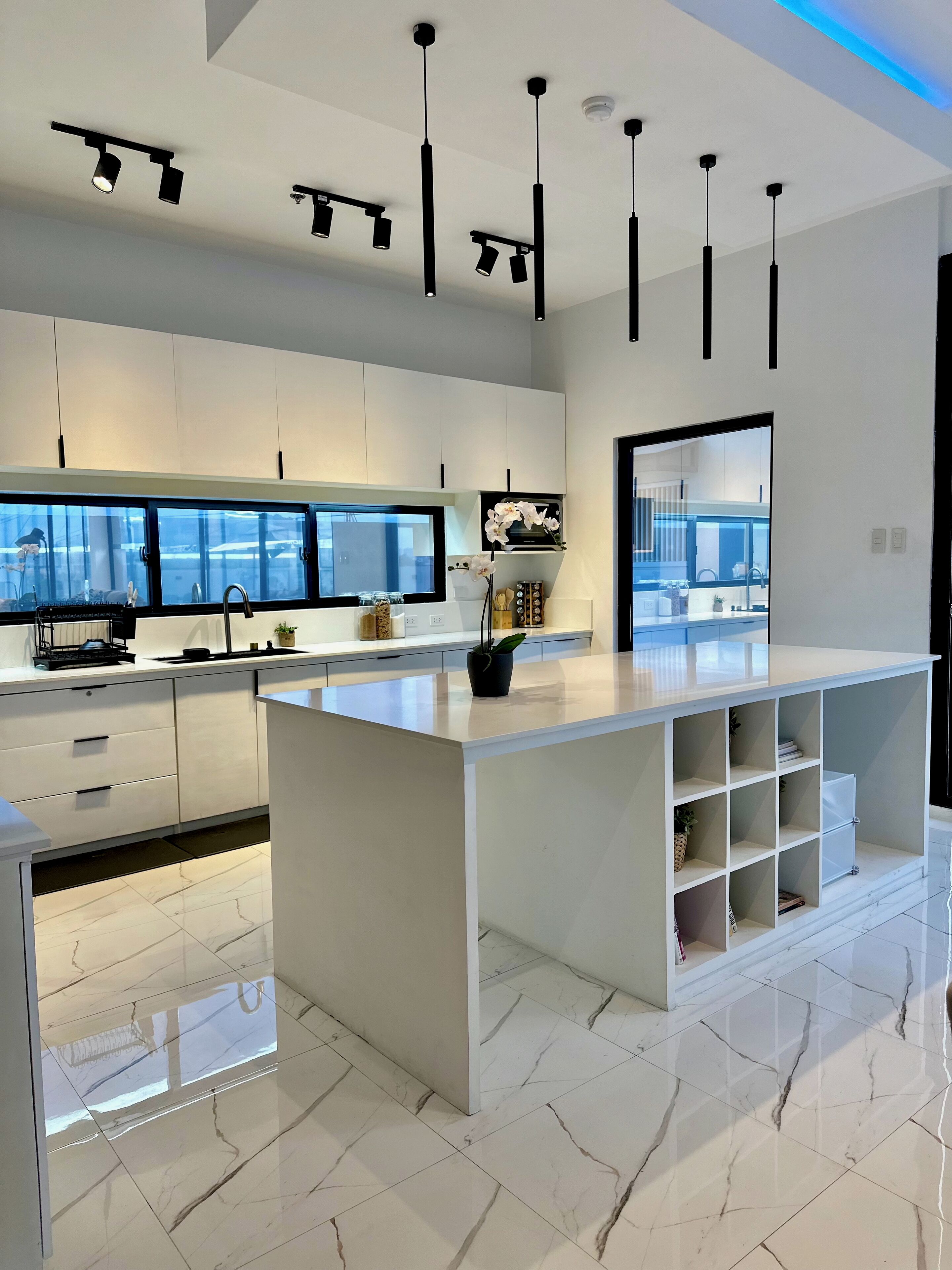 A modern kitchen with white cabinetry, a large island, and pendant lighting.