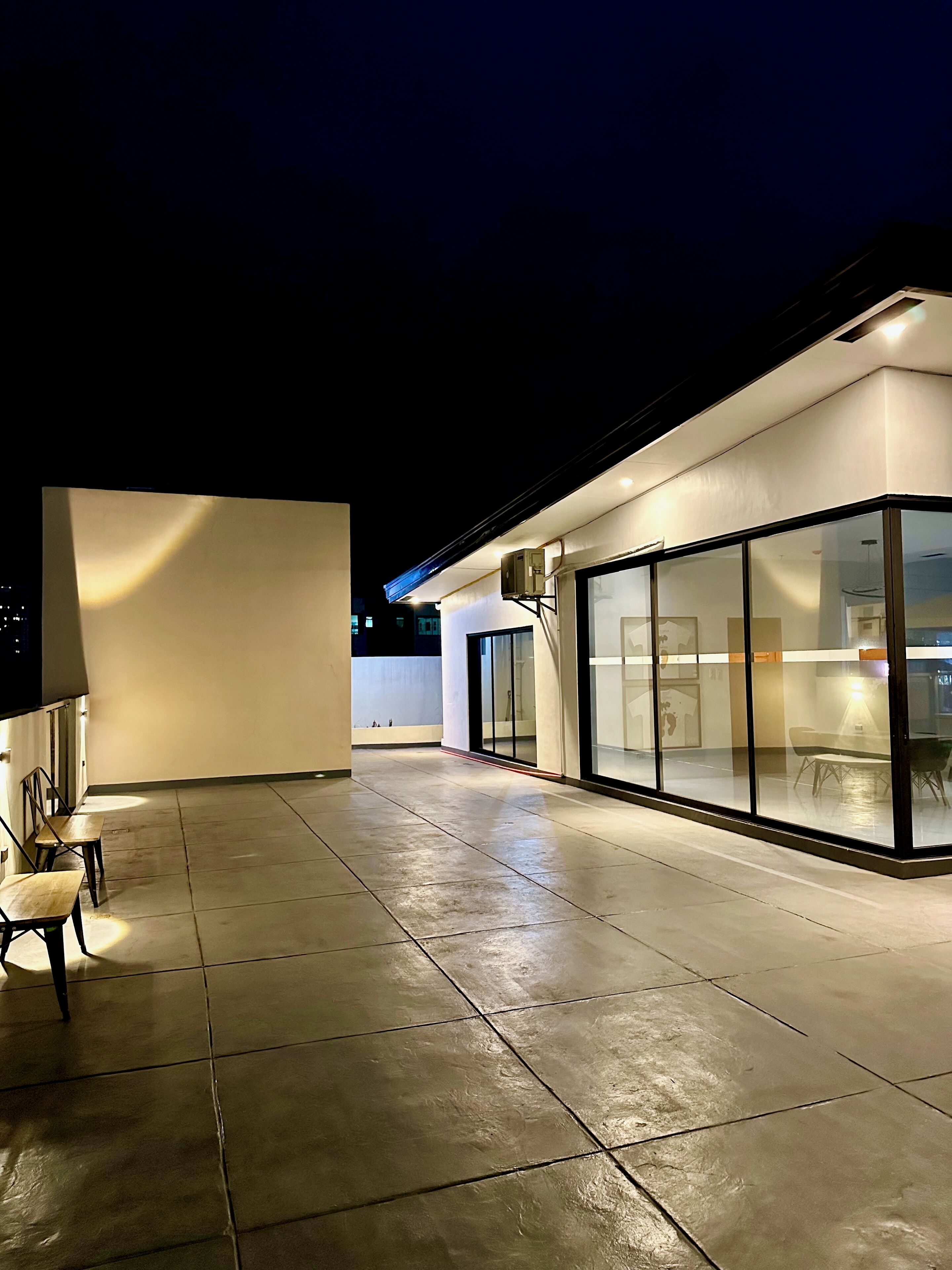 A modern building with a glass facade, a covered outdoor seating area, and a clean, tiled floor.