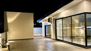 A modern building with a glass facade, a covered outdoor seating area, and a clean, tiled floor.