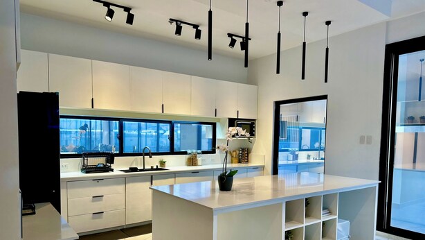 Une cuisine moderne avec des meubles blancs, un sol en marbre et des luminaires suspendus.