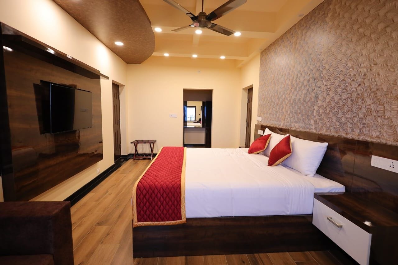A hotel room with a bed, bedside table, and a flat-screen TV mounted on the wall.