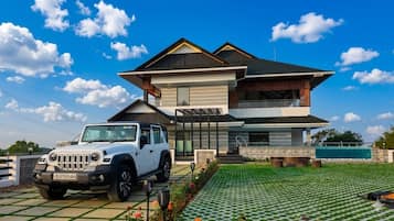 Uma casa moderna de dois andares com um SUV estacionado, um gramado bem cuidado e um céu azul límpido.