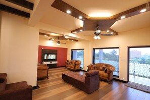 Un amplio salón con diseño moderno, que incluye un sofá modular grande, un televisor de pantalla plana y un balcón con vistas.