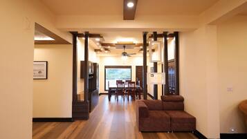 A spacious interior with a wooden floor, a brown sofa, and a dining area with chairs and a table.