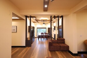 Un interior amplio con piso de madera, un sofá marrón y un comedor con sillas y una mesa.