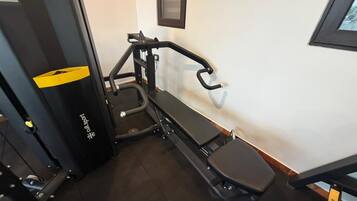 A gym with exercise equipment, a bench, and a wall-mounted mirror.