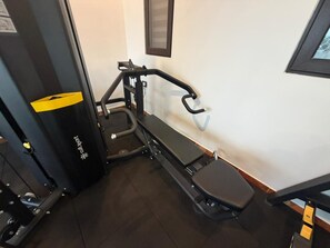 A gym with exercise equipment, a bench, and a wall-mounted mirror. - Plachoos Gardens Kuttikkanam (Kuttikkanam)