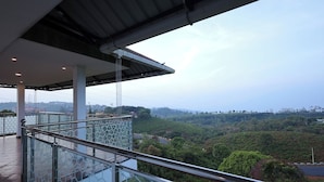 Un balcon doté d’une balustrade en verre donnant sur une vallée verdoyante.