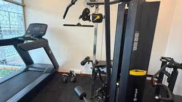Academia com esteira, banco de musculação e diversos equipamentos de ginástica.