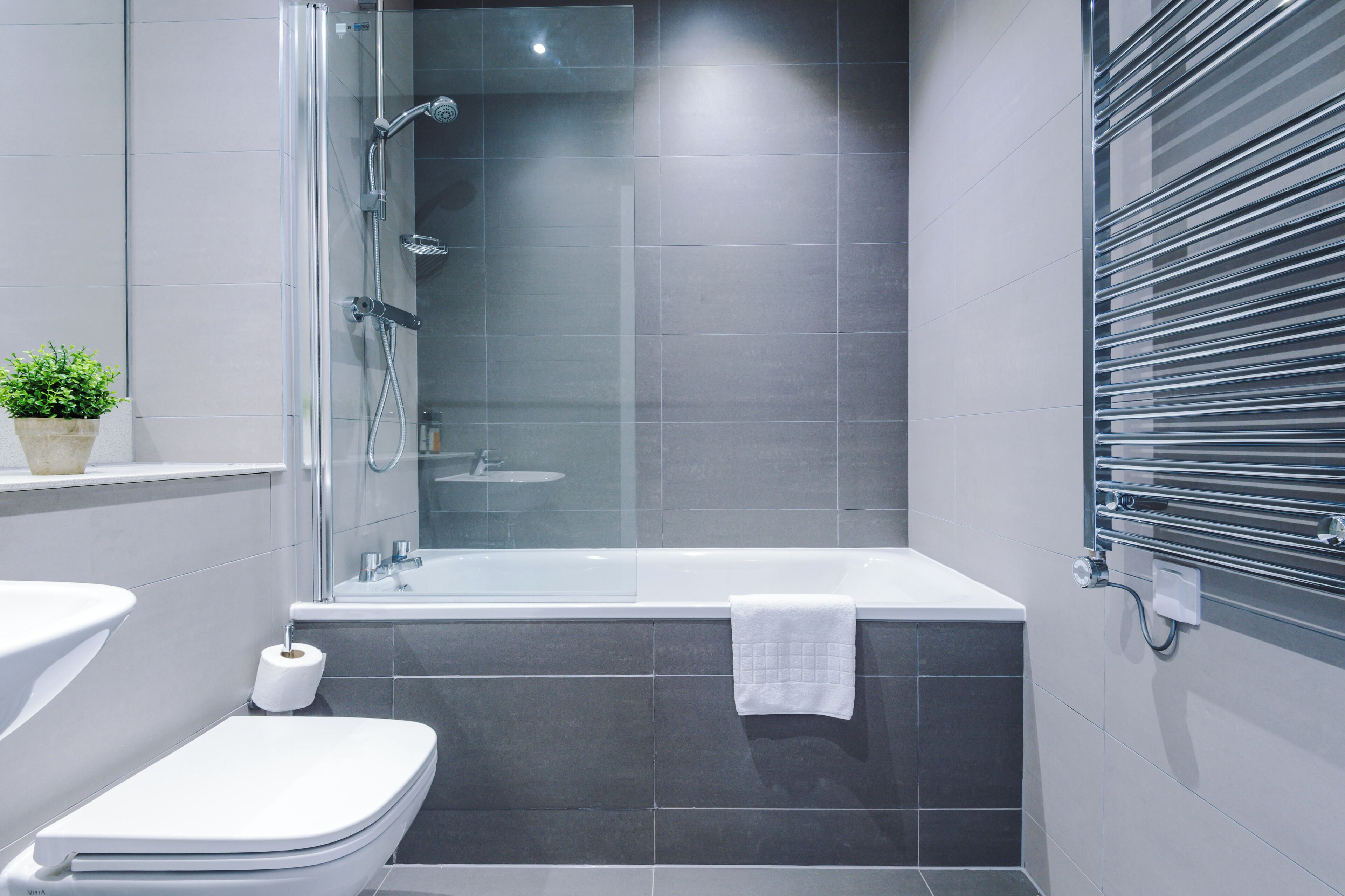 Une salle de bain moderne avec une douche à parois de verre, une baignoire blanche et des toilettes.