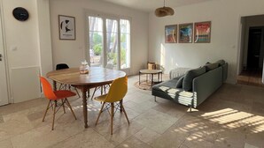Un vaste espace de vie comprenant une table à manger, des chaises colorées, un canapé et un ventilateur de plafond.