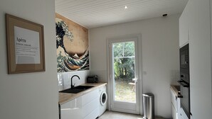 Une cuisine moderne équipée d’un évier, d’un lave-linge et d’une grande fenêtre.