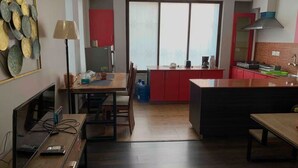 A compact kitchen with a dining area, a large window, and a red cabinet.
