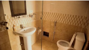 A bathroom with a sink, mirror, toilet, and shower.
