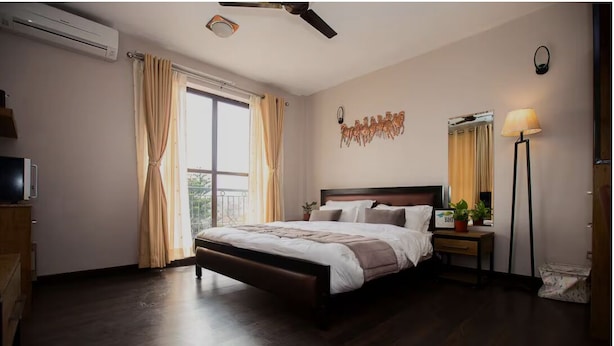 Ein Schlafzimmer mit Bett, Nachttisch, Lampe, Wanddekoration und Klimaanlage.