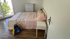 A bedroom with a bed, a nightstand, a bag, and a window. - Studio 2 steps from Saint Charles station (Unknown)