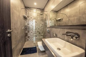 Un bagno moderno con doccia a filo pavimento, una vasca da bagno ampia e uno specchio sopra il lavabo.